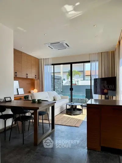 Modern living room with stylish decor and large windows opening to a balcony with a view.