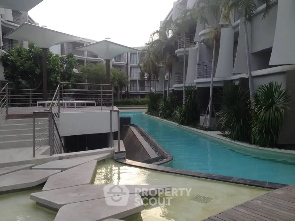 Luxurious modern apartment complex with stunning pool and lush greenery.