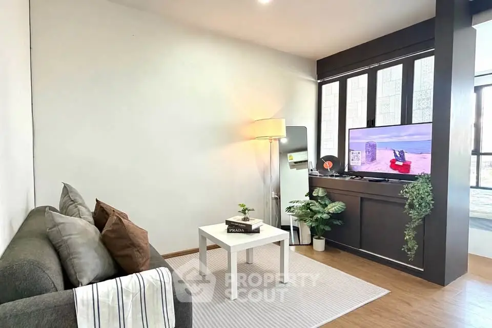Cozy living room with modern decor, featuring a comfortable sofa, stylish lamp, and a flat-screen TV.