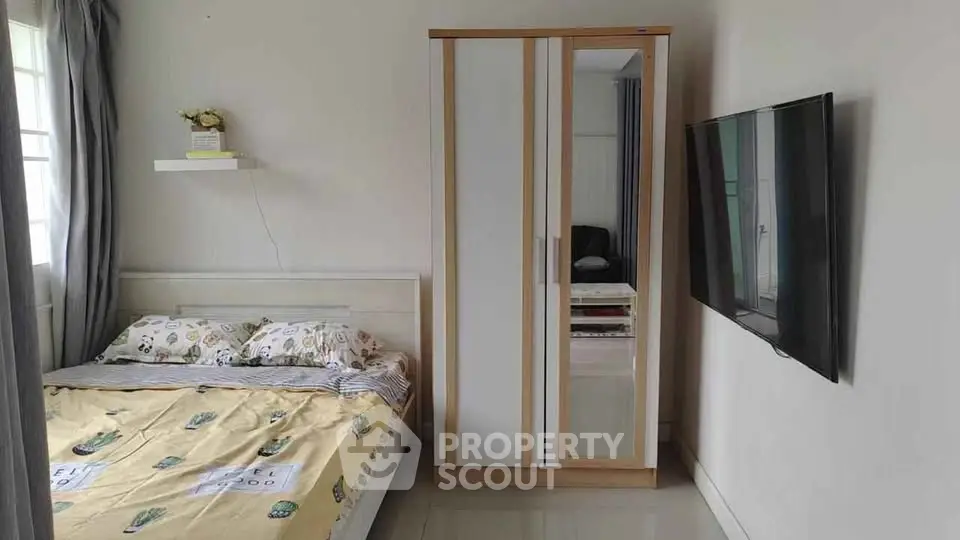 Cozy bedroom with modern wardrobe and wall-mounted TV, perfect for comfortable living.