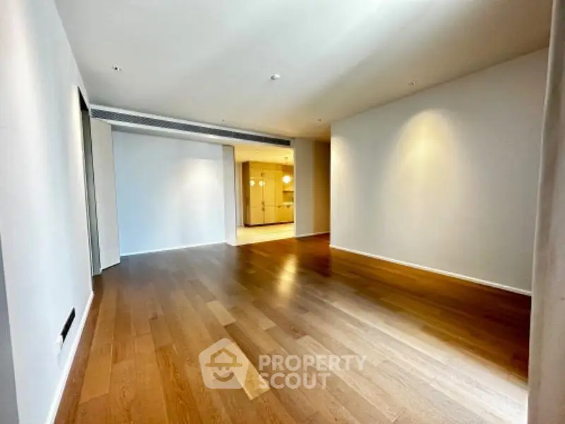 Spacious empty living room with wooden flooring and modern lighting