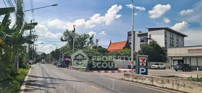 Street view with commercial buildings and parking area under a clear blue sky.