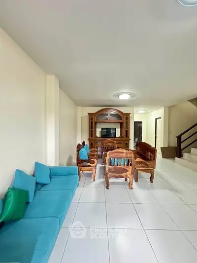 Spacious living room with elegant wooden furniture and modern blue sofa, perfect for relaxation.