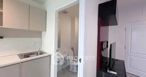 Compact apartment interior with kitchen and bathroom view, featuring modern fixtures and sleek design.