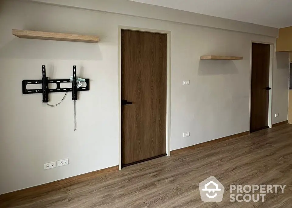 Spacious room with wooden flooring and wall-mounted TV bracket