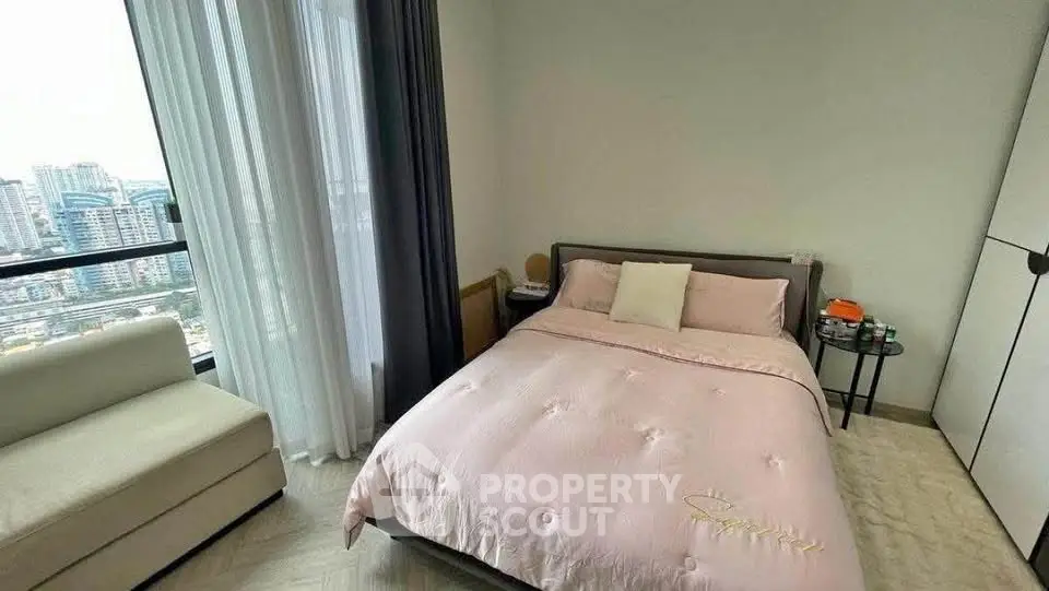 Cozy bedroom with city view, modern decor, and ample natural light.