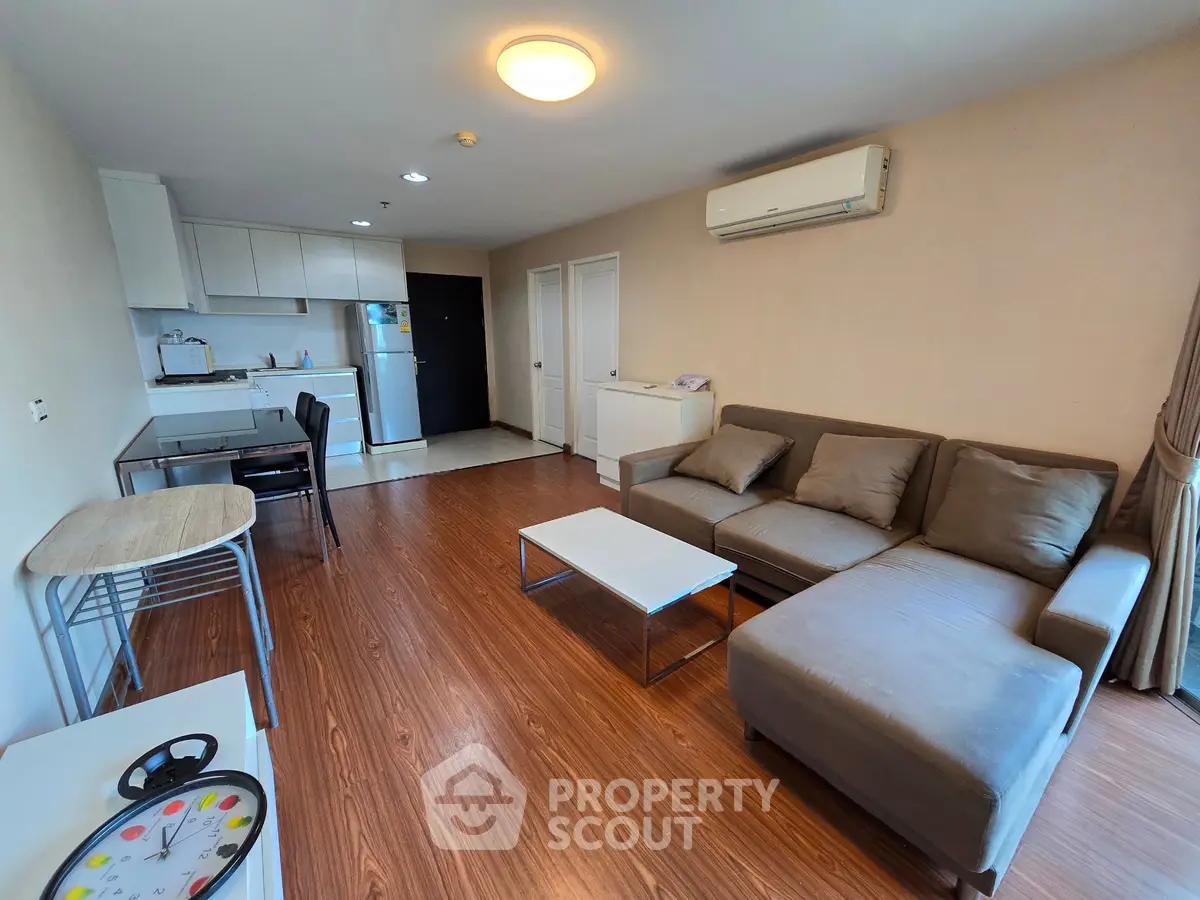 Spacious living room with modern furniture and open kitchen layout in a cozy apartment.