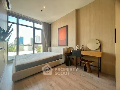 Modern bedroom with large window and stylish decor in urban apartment.