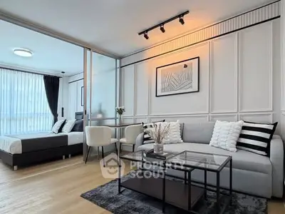 Modern living room with stylish decor and adjacent bedroom in open layout apartment.