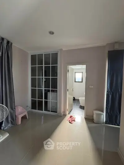 Spacious room with modern design and attached bathroom, featuring sleek flooring and ample natural light.