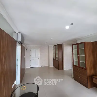 Spacious living room with modern wooden cabinets and sleek tile flooring
