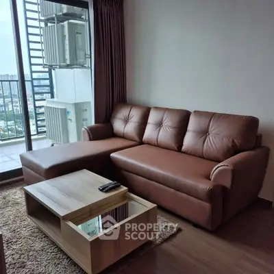 Modern living room with brown leather sofa and city view balcony in high-rise apartment.