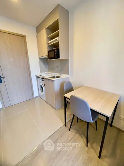 Compact modern kitchen with integrated washing machine and microwave, perfect for urban living.