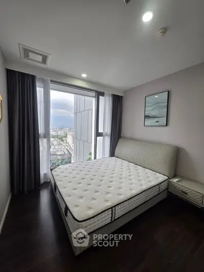 Modern bedroom with city view, featuring a large window and stylish decor.