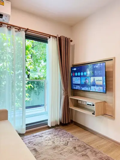 Modern living room with wall-mounted TV and large window overlooking greenery.