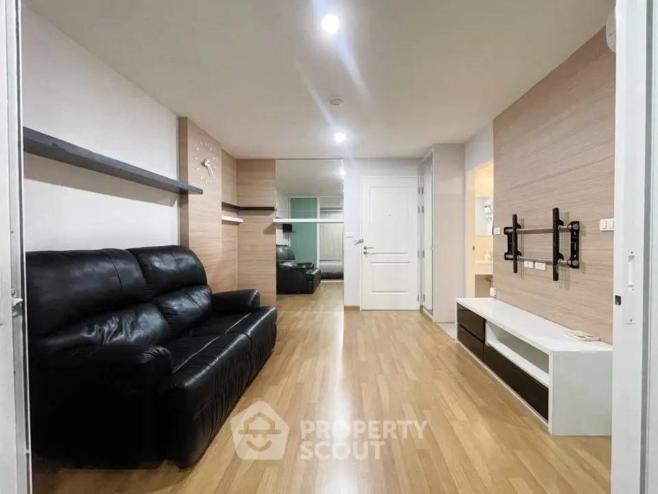 Modern living room with sleek black leather sofa and wooden flooring