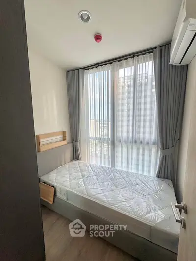 Cozy bedroom with large window and modern furnishings in a stylish apartment.