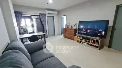 Spacious living room with modern decor and large TV, perfect for relaxation.