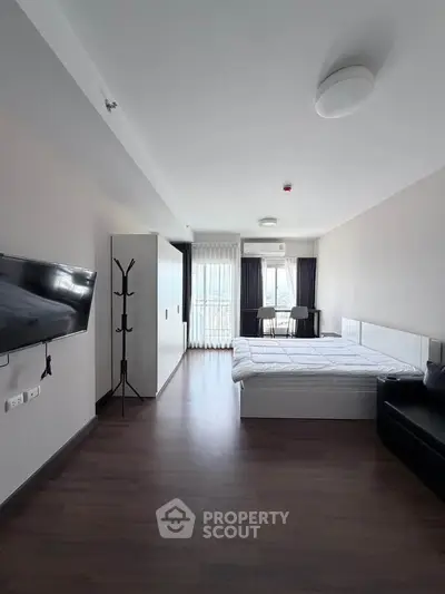 Spacious modern bedroom with sleek furniture and large window for natural light.