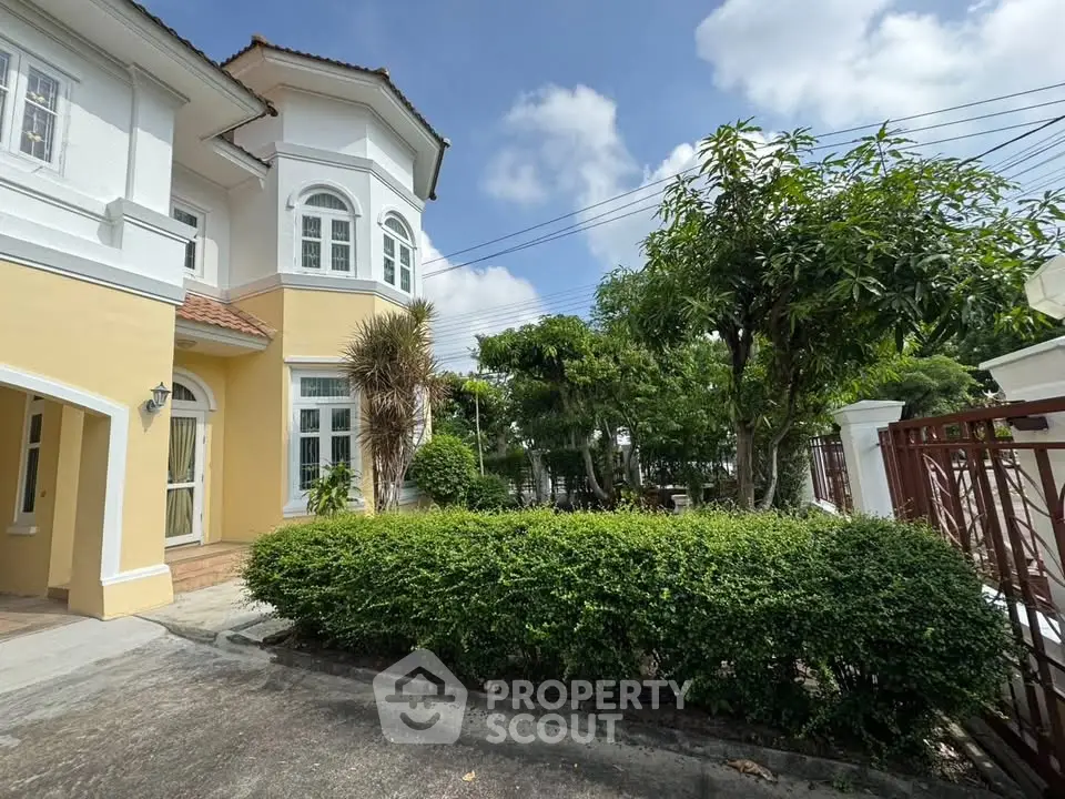 Charming two-story house with lush garden and classic architecture under a clear blue sky.