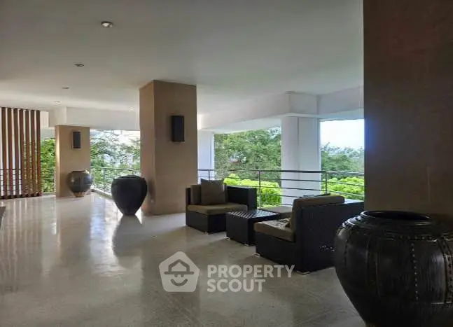 Spacious and elegant building corridor with modern seating and lush greenery view.