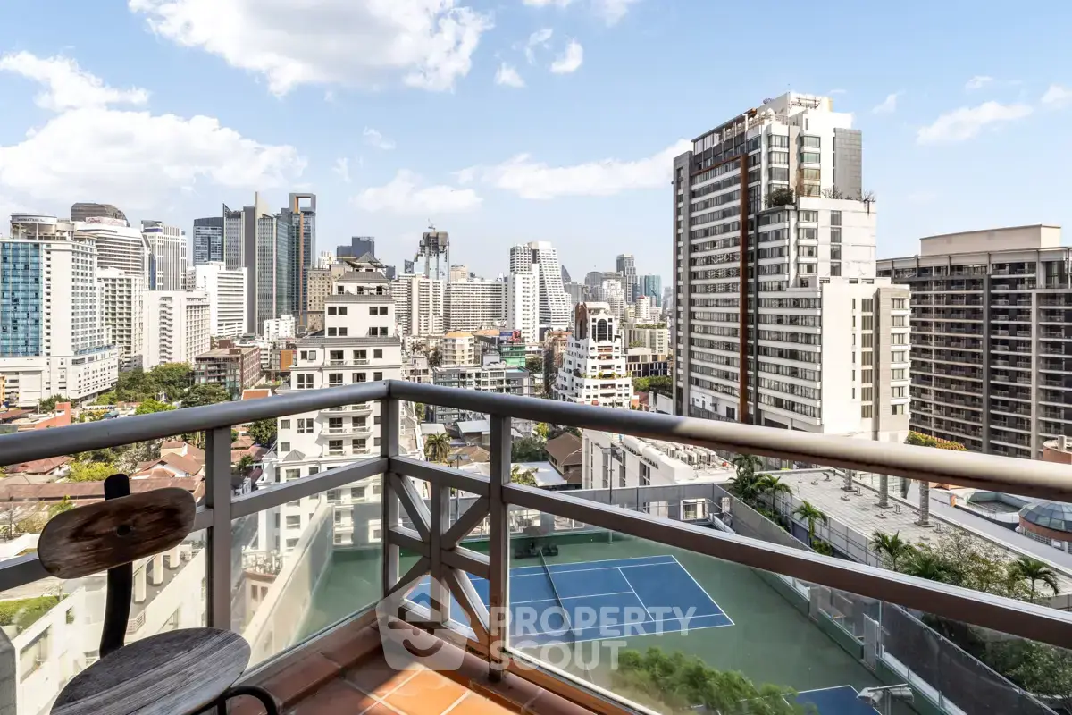 Stunning cityscape view from a high-rise balcony overlooking tennis courts and skyscrapers.