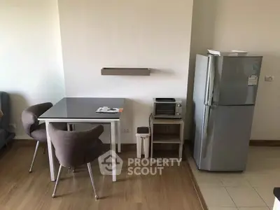Modern kitchen corner with dining table, chairs, and stainless steel fridge in cozy apartment.