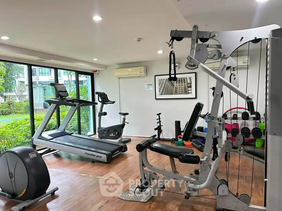 Modern gym with state-of-the-art equipment and garden view in luxury residential complex.