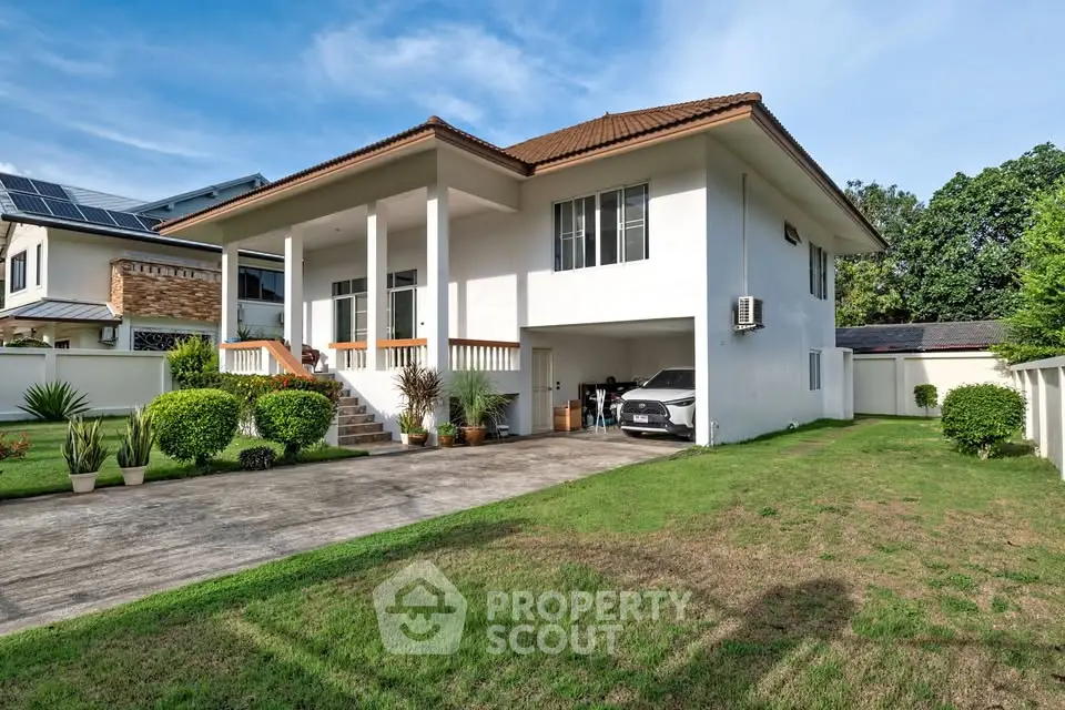Charming two-story house with spacious driveway and lush green lawn, perfect for family living.