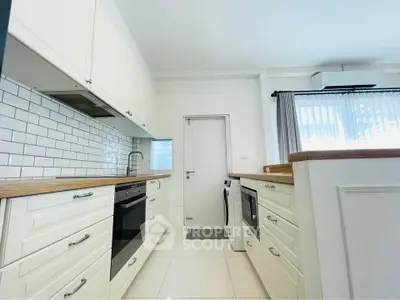 Modern kitchen with white cabinetry and built-in appliances in a bright, airy space.