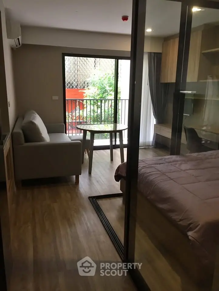 Modern studio apartment with glass partition, cozy living area, and balcony view.