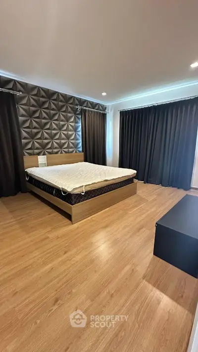 Spacious modern bedroom with stylish wall design and wooden flooring