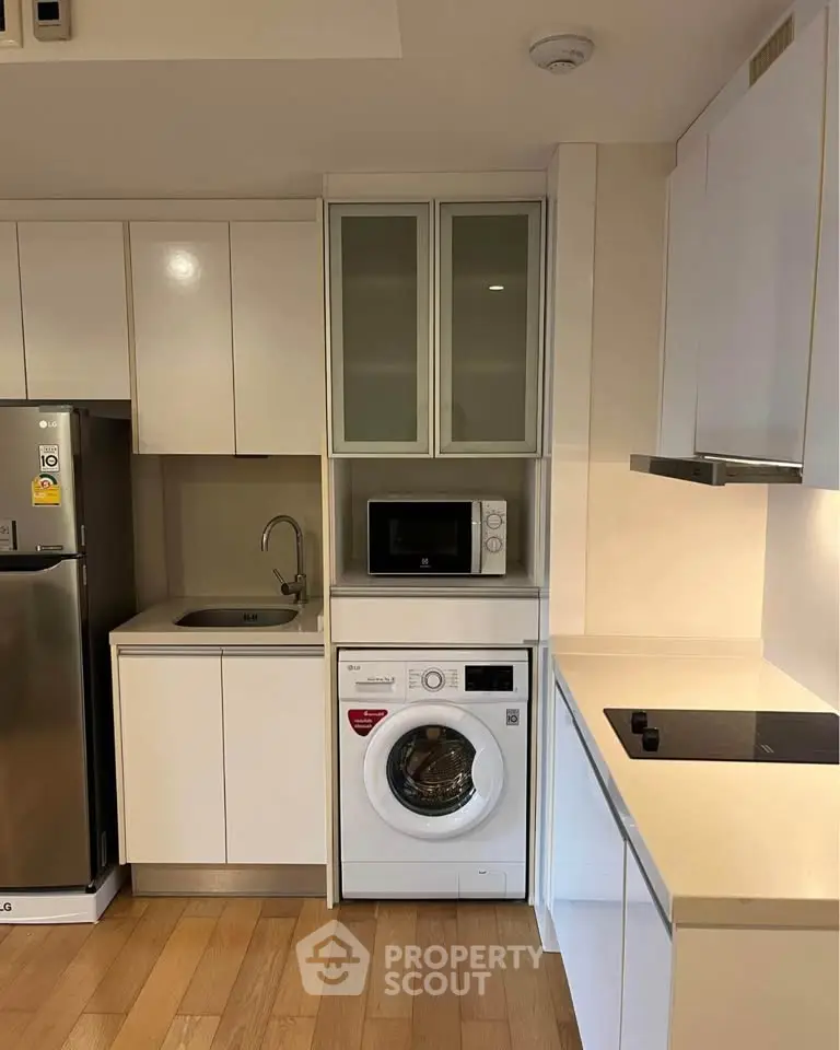 Modern kitchen with sleek appliances and washing machine in compact layout.