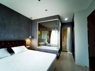 Modern bedroom with stylish decor and large mirror, featuring a cozy bed and elegant lighting.