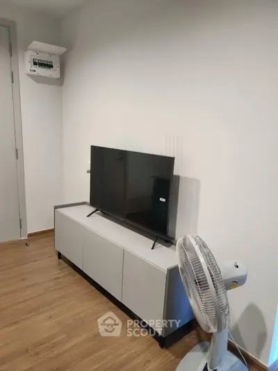 Modern living room with sleek TV stand and fan on wooden flooring