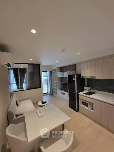 Modern open-plan living room with kitchen, featuring sleek cabinetry and contemporary furnishings.