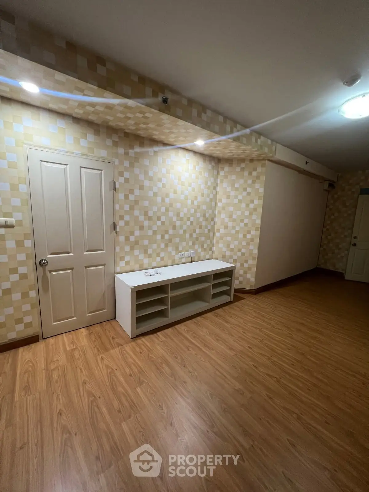 Spacious living room with modern wood flooring and stylish wall design, perfect for cozy gatherings.