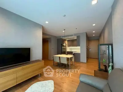 Modern living room with open kitchen, stylish furniture, and wooden flooring.