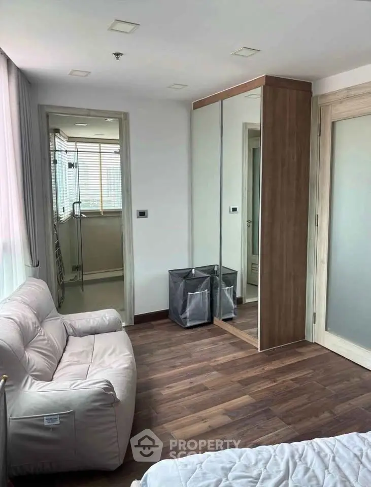 Cozy bedroom with mirrored wardrobe and comfortable seating in modern apartment.