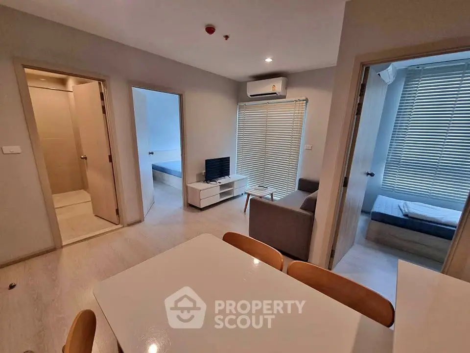 Modern apartment interior with open living and dining area, featuring sleek furniture and natural light.