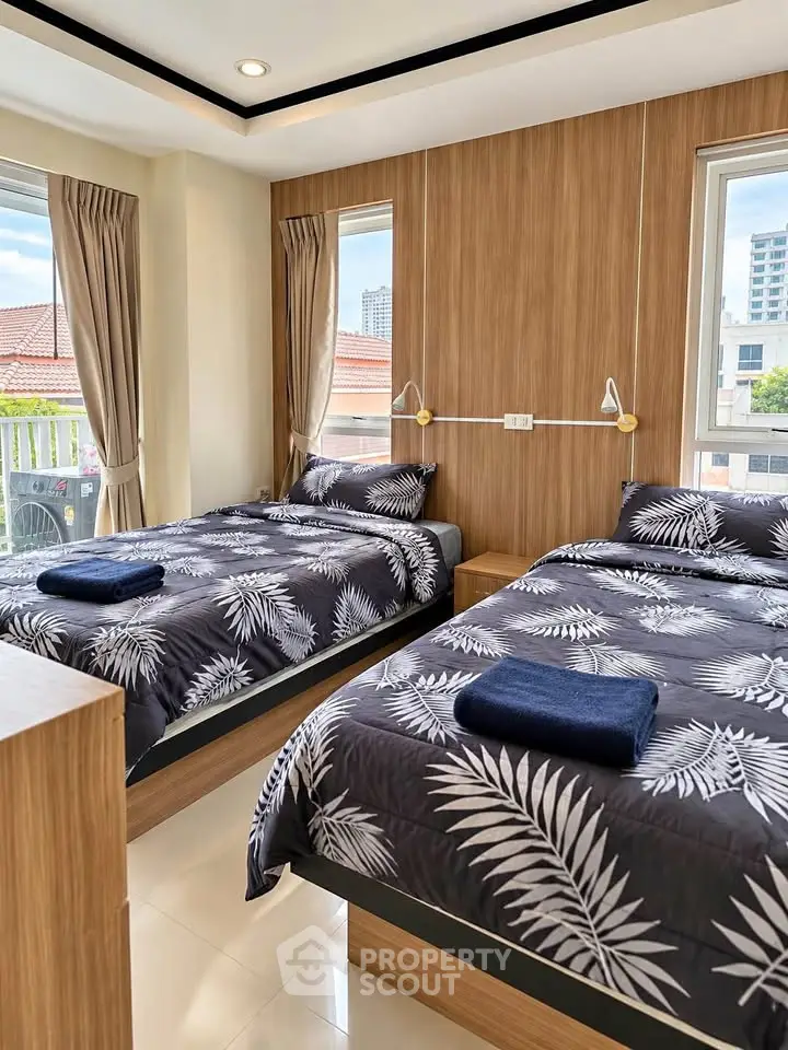 Modern bedroom with twin beds and large windows offering city views
