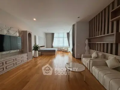 Spacious modern living room with wooden flooring, stylish furniture, and large window for natural light.