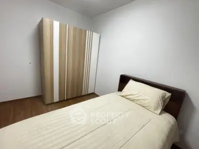 Cozy minimalist bedroom with wooden wardrobe and single bed, perfect for a peaceful retreat.