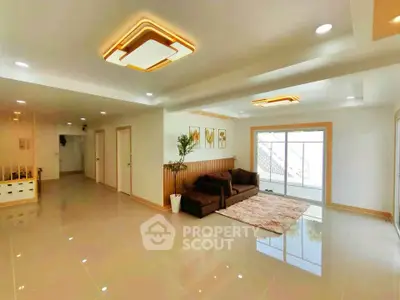 Spacious modern living room with elegant lighting and cozy seating area, perfect for relaxation and entertainment.