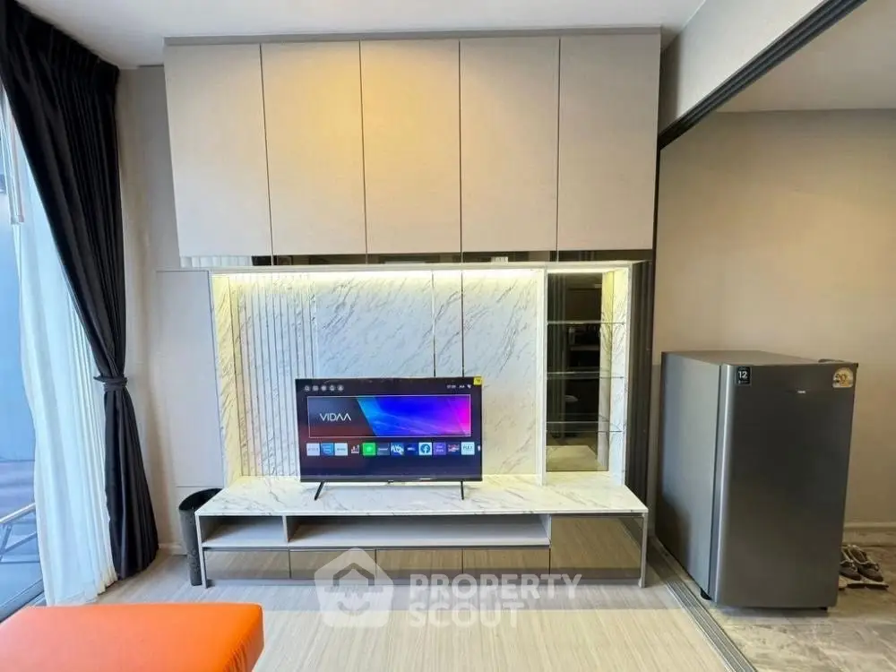 Modern living room with sleek TV unit and marble accents, adjacent to a stylish kitchen area.