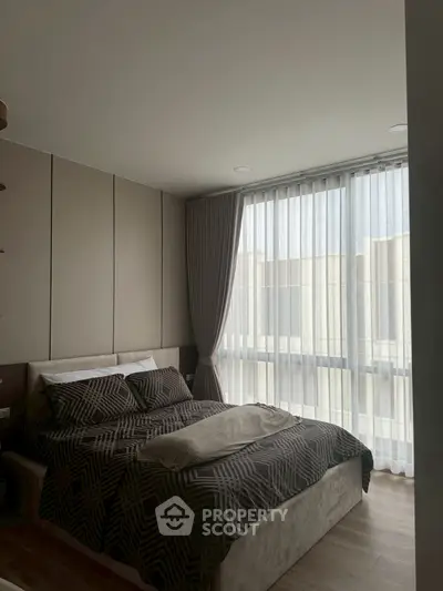 Modern bedroom with large windows and stylish decor in a contemporary apartment.