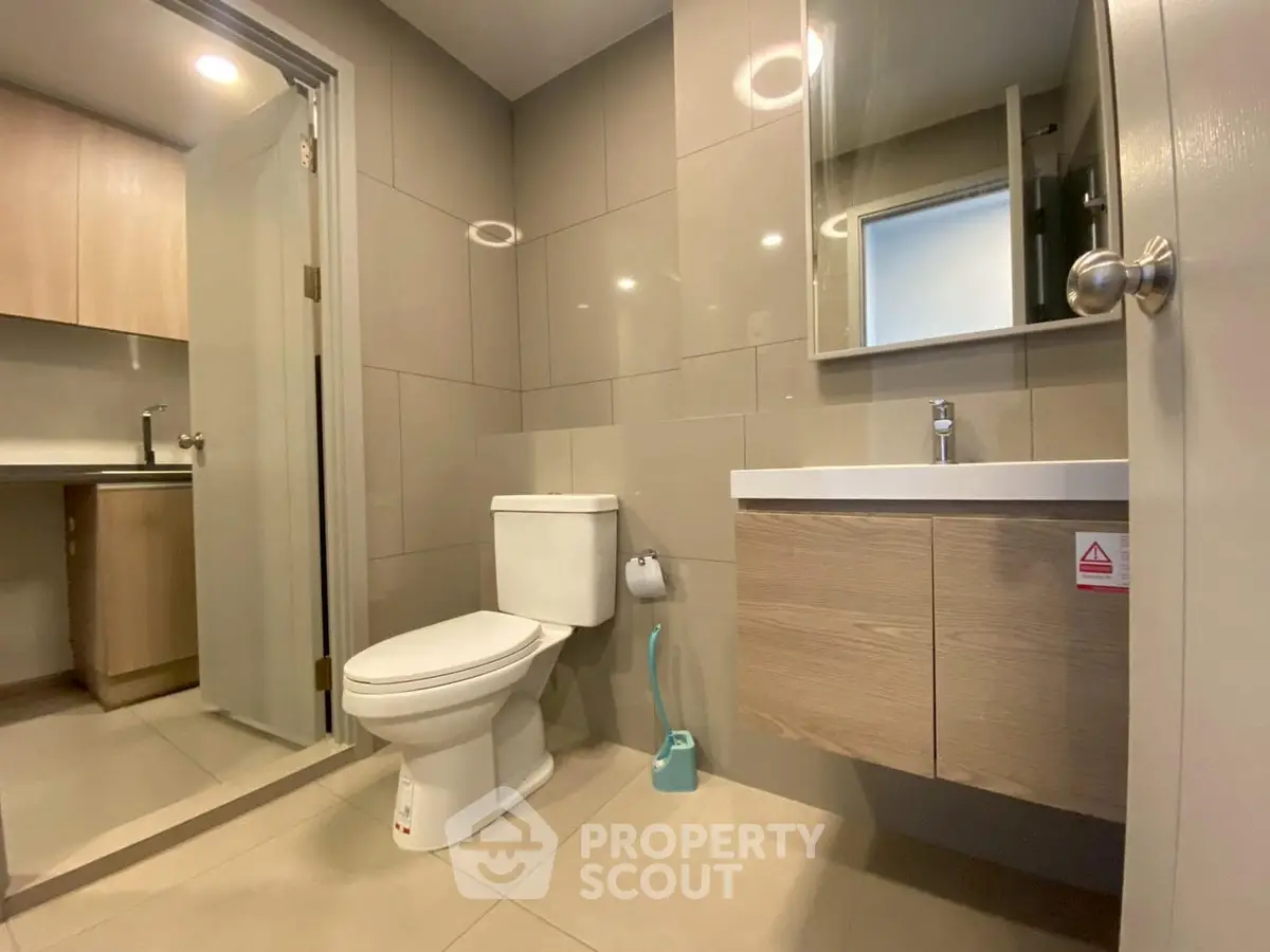 Modern bathroom with sleek fixtures and neutral tones, featuring a toilet and vanity.