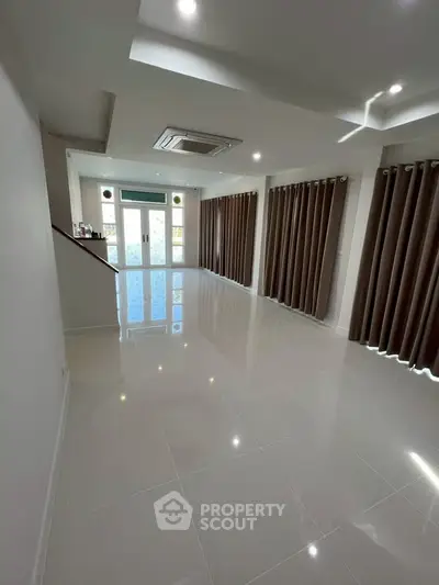 Spacious living room with glossy tiled floors and large windows for natural light.