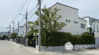 Charming corner unit house with lush greenery and modern architecture in a serene neighborhood.