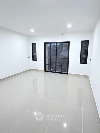 Spacious modern living room with sleek tile flooring and large windows for natural light.